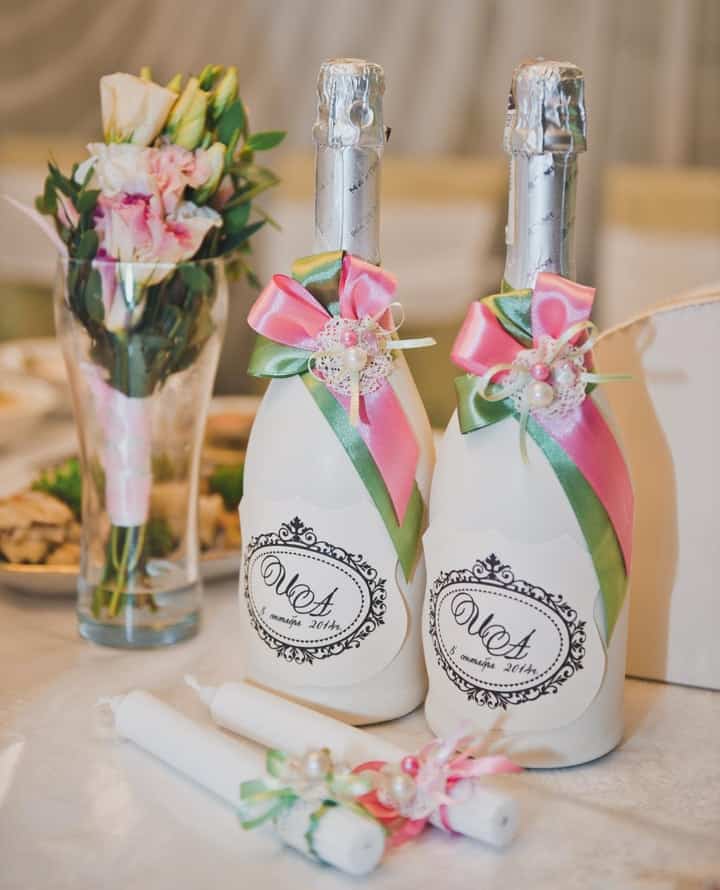 Botellas decoradas para boda y flores en mesa.
